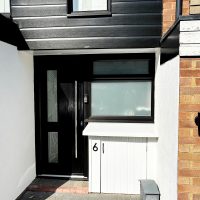 Black cladding and black front door, next to repaired electricity meter cupboard