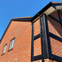 Repainted black mock Tudor beams below white soffits and black fascias