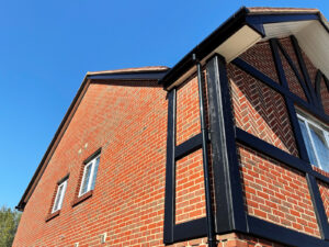 Repainted black mock Tudor beams below white soffits and black fascias